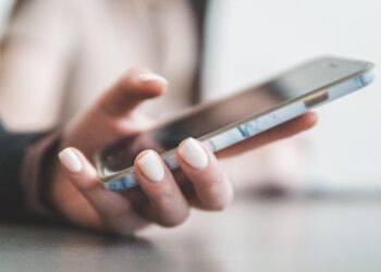 Person holding phone and typing phone number for text-to-donate fundraising campaign